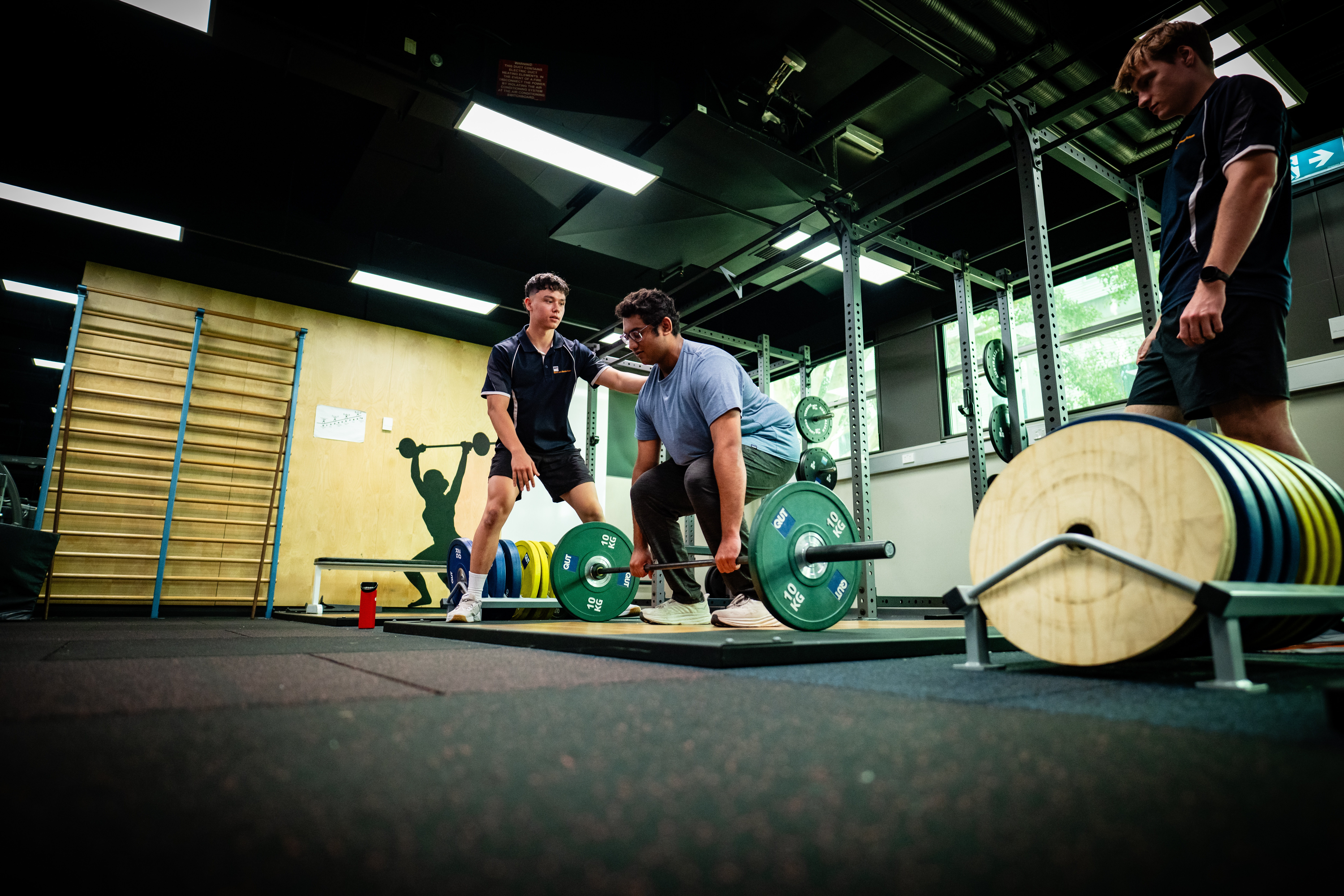 Students working with weight lifting equipment in a gym