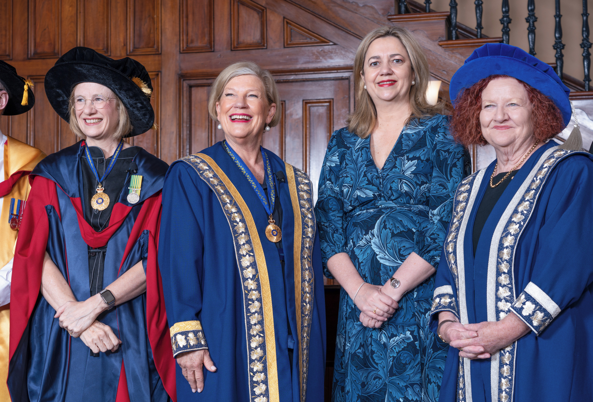 four women stand in blue robes 