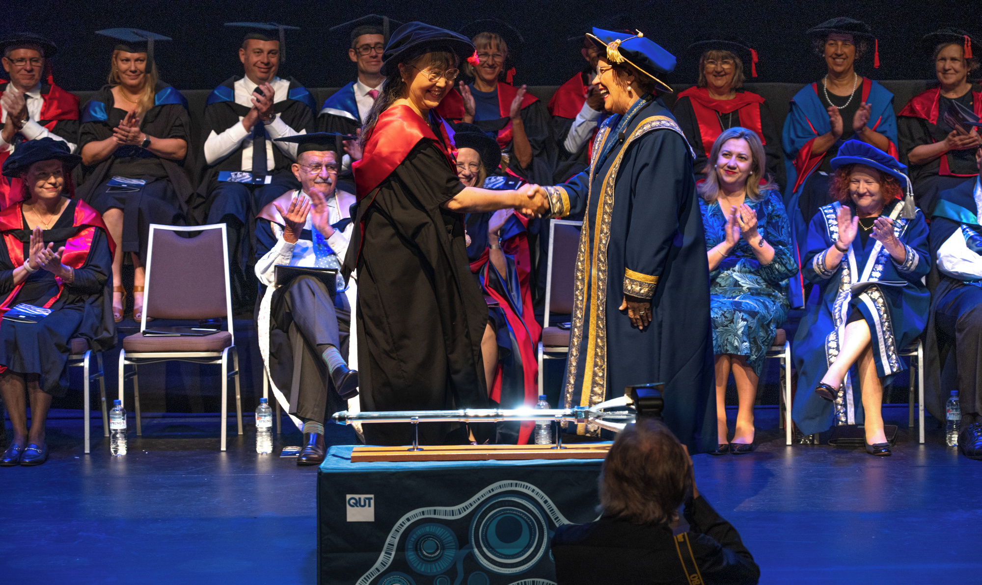 woman in academic gown shakes hand of another woman in academic gown