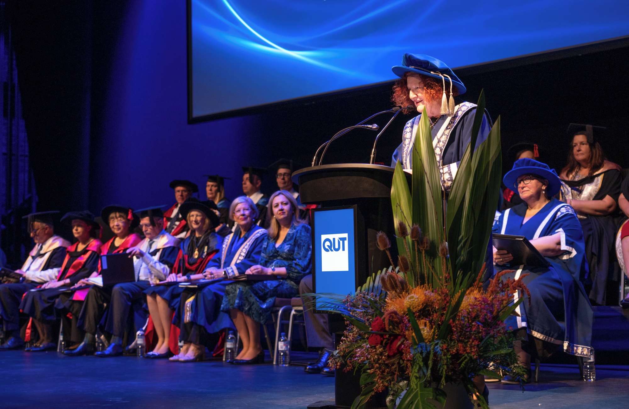 Woman in academic robes addresses audience